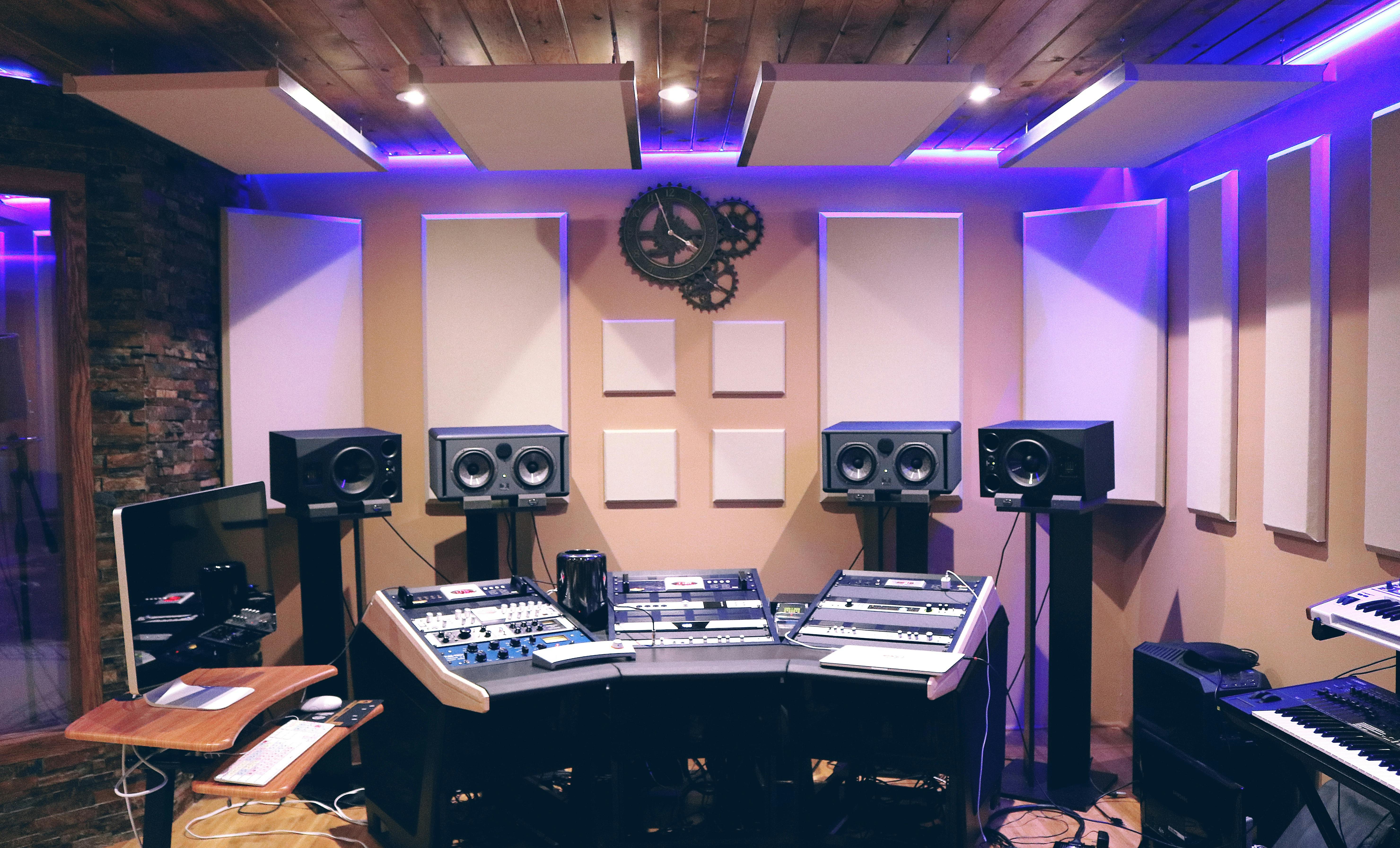 Audio and media studio interior with control desk, speakers and acoustic panels.